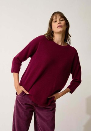 Maglione borgogna a maglia con scollatura rotonda, maniche 3/4 e vestibilità rilassata. Abbinato a pantaloni in corduroy borgogna a costine.