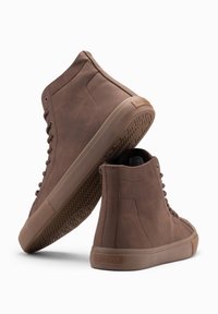 Zapatillas de cuero marrón de caña alta con puntera redonda, suela plana de goma y diseño de cordones. Presenta un patrón de rodadura texturizado.