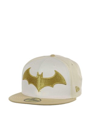 Cream snapback cap featuring a golden Batman logo on the front. The bill is a darker cream, with stitching accents and a flat visor design.