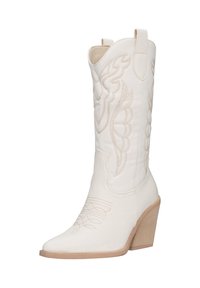 Bota cowboy de cuero blanco con punta afilada, costuras decorativas y dos lengüetas. Cuenta con un tacón de bloque de madera con un acento texturizado.