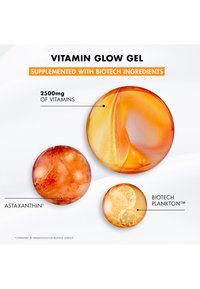 Żel Vitamin Glow z trzema okrągłymi kapsułkami w różniących się odcieniach pomarańczowego, z teksturami podkreślającymi astaksantynę i biotechnologiczny plankton.