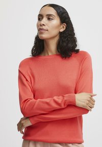 Maglione a maglia corallo con collo a giro, maniche lunghe e polsini a coste. Texture liscia e vestibilità rilassata, con cuciture sulle spalle sottili.