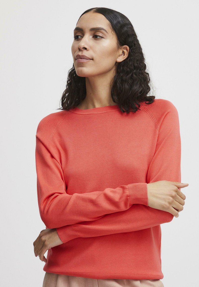 Maglione a maglia corallo con collo a giro, maniche lunghe e polsini a coste. Texture liscia e vestibilità rilassata, con cuciture sulle spalle sottili.
