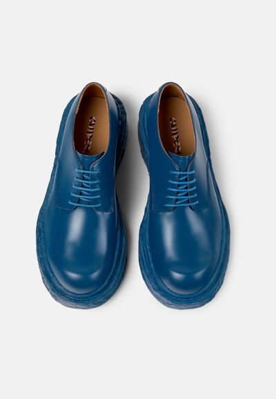 Blue leather shoes with a glossy finish, featuring a rounded toe, shallow laces, and a thick textured sole for added durability.