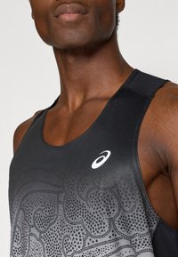 Μαύρο αθλητικό μπλουζάκι χωρίς μανίκια με γραντίνες σχέδ ιο και σημειακές λεπτομέρειες. Φτιαγμένο από κομψό, αναπνεύσιμο ύφασμα. Δεσπόζουσα λευκή λογότυπο στο στήθος.