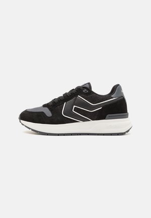 Black and gray sneakers with a suede and mesh upper, featuring contrasting white detailing, round laces, and a thick, cushioned outsole.