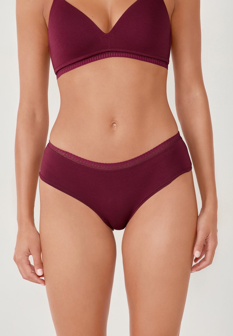 Set di reggiseno bordeaux e mutande a vita alta, realizzato in tessuto morbido con una superficie liscia e cuciture decorative lungo i bordi.