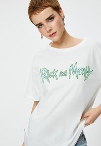 T-shirt bianca in cotone con una grande grafica stilizzata verde di "Rick and Morty" al centro. Collo a giro e maniche corte.