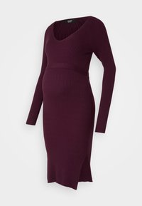 Maternity dress in dark purple, ribbed knit fabric. Features long sleeves, a deep V-neck, belted waist, and side slits for comfort.