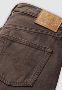 Καφέ τσέπη πίσω σε τζιν Levi's με δερμάτινο έμπλαστρο της μάρκας που εμφανίζει το λογότυπο Levi Strauss & Co. και λεπτομέρειες ραφής.