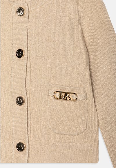 Beige kardigán bordázott anyagból, aranyszínű gombokkal és logós díszítésű zsebbel. Puha tapintású, enyhén fényes.