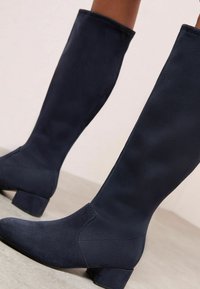 Botas de navy oscuro hasta la rodilla, hechas de un tejido suave, con tacón cuadrado, punta afilada y diseño sin costuras.