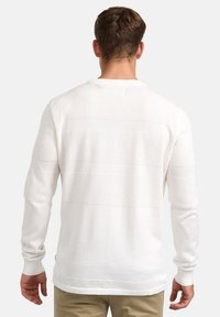 Weißer Strickpullover mit einem strukturierten Muster und horizontalen Streifen. Lange Ärmel und rundem Ausschnitt. Weicher Stoff, lässige Passform.