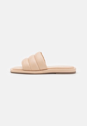 Sandale plate beige à enfiler avec trois brides rembourrées sur le pied et une semelle légèrement texturée pour une meilleure adhérence.