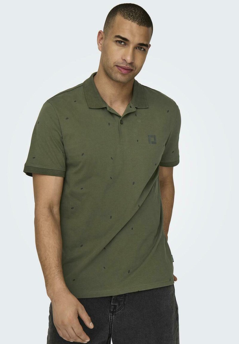 Olivgrünes Polo-Shirt aus Baumwolle mit dezenten Blattmustern, kurzen Ärmeln, einem Kragen und einem Logo auf der linken Seite.