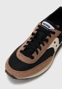Svart og brunt sneaker med overdel i semsket lær og mesh, med svarte lisser, en hvit logo-patch og en teksturert gummisåle.