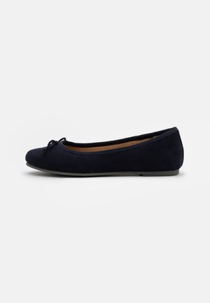 Chaussure plate ballerine noire avec un petit nœud à l'avant et une semelle plate, vue de côté sur fond blanc.