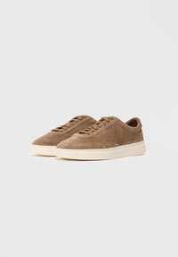 Pair of brown suede sneakers with cream rubber soles and matching laces, low-top style, embossed with "BOSS" on the side.