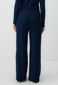 Navy wijde broek gemaakt van textiel met een golvend patroon, met een hoge taille en subtiele stretch voor comfort.