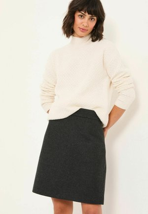 Cream knit sweater with a textured pattern and a high collar, paired with a dark gray A-line skirt featuring a subtle vertical stripe.
