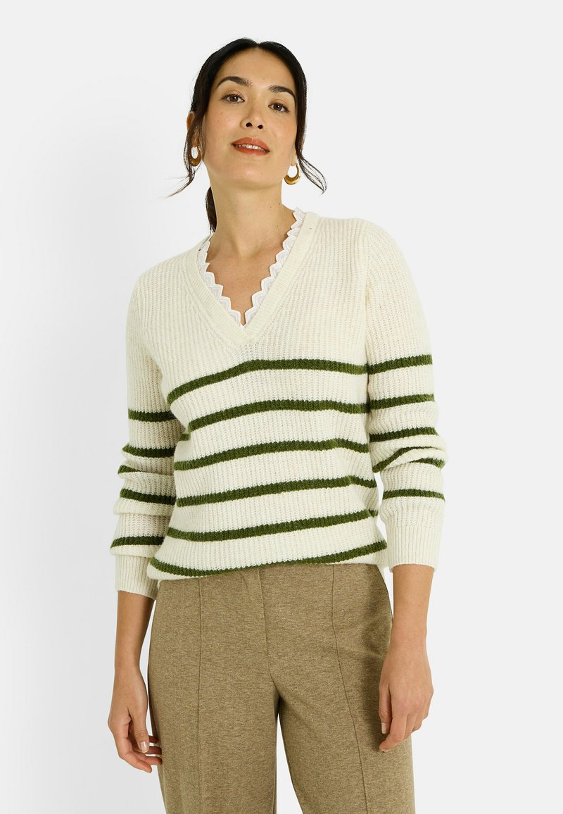 Suéter de punto color crema con rayas horizontales verdes, escote en V, textura acanalada y cuello con borde festoneado. Combina con pantalones marrones.