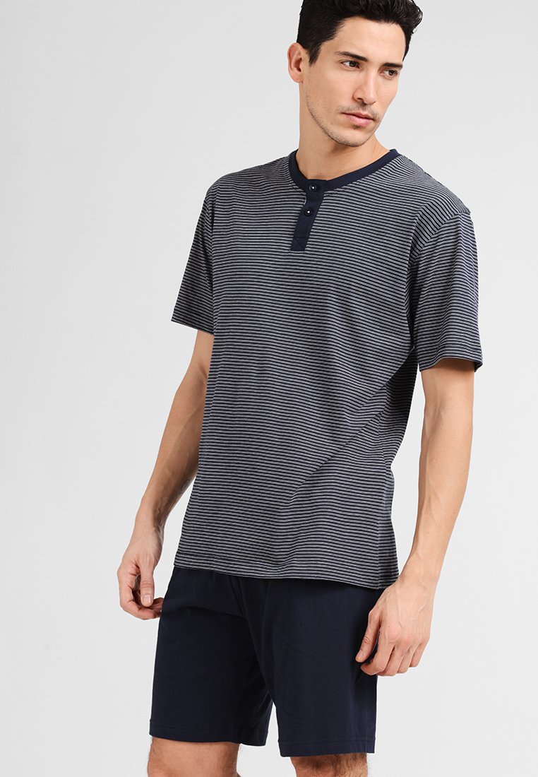 T-shirt rayé bleu marine et gris à manches courtes et col rond, avec une patte de boutonnage. Associé à un short bleu marine.