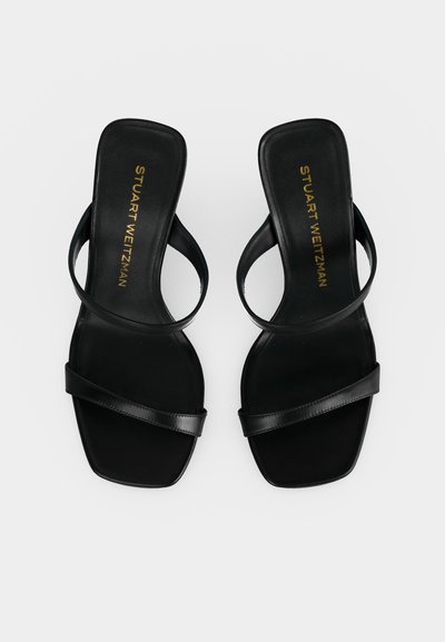 Sandales noires en cuir à bout ouvert avec deux fines brides et bout carré, avec le logo doré "Stuart Weitzman" sur les semelles.