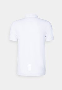 Camisa polo blanca con un cuello clásico, mangas cortas y una textura de tela suave. Detalle notable: rayas verticales en la parte baja de la espalda.