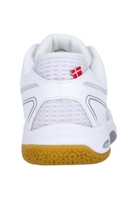 Vit sportskor med övre i nätmaterial, grå accenter och en texturerad gummisula. Har en liten detalj med röd och vit flagga på hälen.