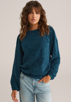 Maglione verde acqua con trama, maniche lunghe e collo a giro. Polsini e orlo a coste con motivi ondulati su tutto il tessuto.