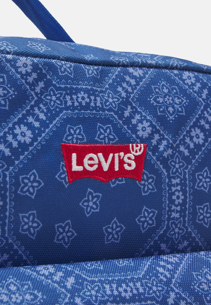 Sac en tissu bleu avec un motif floral, arborant un logo "Levi's" rouge bien en évidence brodé à l'avant. Matériau durable avec une finition texturée.