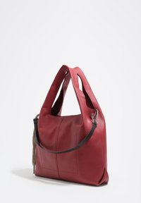Rdeča usnjena torba s dvojno ročico, ki ima teksturirano stransko ploščo, gladko površino in subtilne šive. Kovina kot okrasni dodatek.