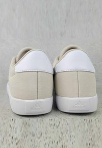 Sneaker in camoscio beige con dettagli in pelle bianca e suola in gomma. Il design semplice presenta un tacco arrotondato e un logo a marchio sul retro.