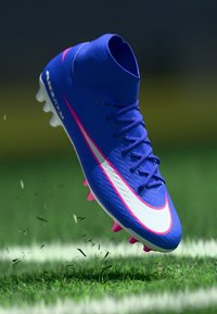 Ποδοσφαιρικό παπούτσι Nike σε ζωηρό μπλε χρώμα με ροζ πινελιές, ελαφρύς σχεδιασμός, υφή στο επάνω μέρος και ορατά καρφιά για πρόσφυση στο γρασίδι.