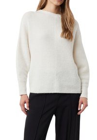 Elfenbeinfarbener Rippstrickpullover mit rundem Ausschnitt und langen Ärmeln, der eine weiche Textur und eine lockere Passform aufweist. Kombiniert mit schwarzen Hosen.