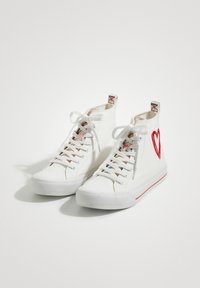 White high-top sneakers with fabric upper, red heart embroidery, colorful patterned lining, and white laces; textured rubber sole with red accent.