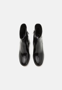 Bottes de cheville en cuir noir avec une finition lisse, dotées d'une fermeture éclair sur le côté extérieur et d'un design à bout rond.