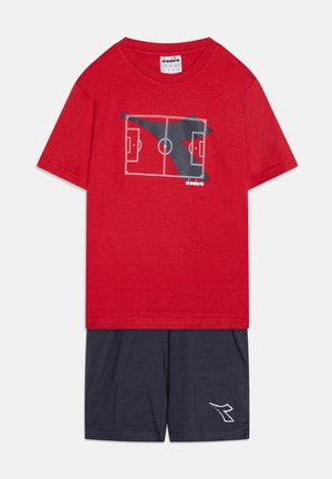 Rød T-shirt med grafik af en fodboldbane, parret med navy shorts med et hvidt logo. 100% bomuldsstof, afslappet pasform, korte ærmer.