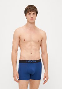 Modré bavlnené boxerky s čiernym pásom a modrým logom Levi's. Dizajn je priliehavý s hladkou textúrou.