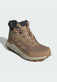 Braune wasserdichte Wanderschuhe mit strukturiertem Mesh-Obermaterial, Gummisohle und gepolsterter Kragen. Verfügt über ein Schnürsystem und das Markenlogo an der Seite.