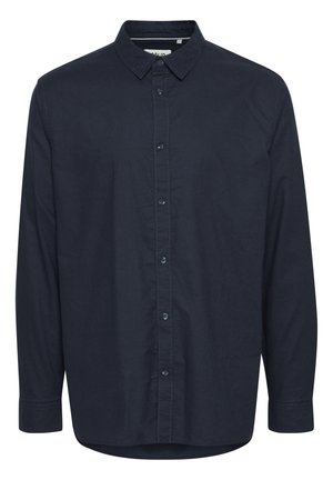 Mornarijeva plava košulja sa dugim rukavima, šiljastim kragnom i džepom na prsima. Izrađena od lagane tkanine s suptilnom teksturom i detaljima od dugmadi.