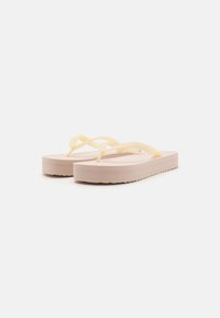 Pink platform flip-flops with yellow rubber straps intersecting over the top. Features textured sole and printed branding on one strap.