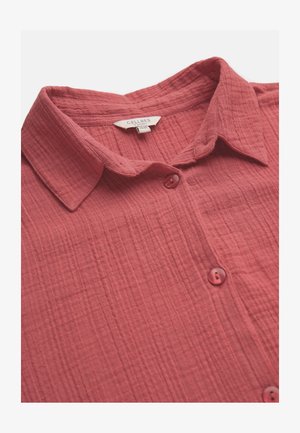 Red textured button-up shirt with a collar and label reading "Cellbes of Sweden," shown in close-up on a white background.