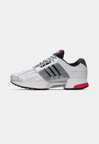 Witte sportschoenen met zwart en rode accenten, voorzien van een textuur-mesh bovenkant en een gevoerde zool voor steun en flexibiliteit.