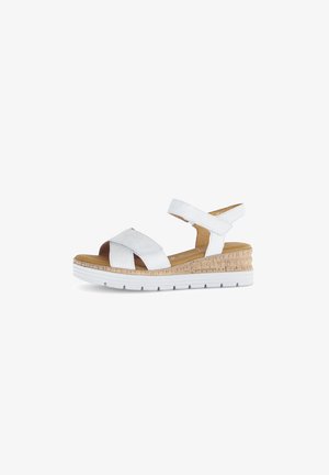 White sandal with cross-strap design, cork wedge heel, and white rubber sole. Features adjustable ankle strap and smooth texture.