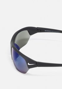 Black sports sunglasses with a wraparound design, gradient lenses transitioning from gray to purple, featuring a Nike logo on the frame.