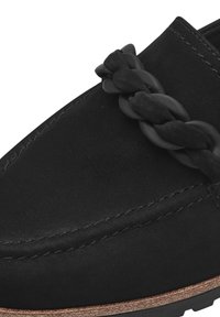 Mustat loaferit, joissa on punottu yksityiskohta edessä, valmistettu sileästä nahasta, joka sisältää mokkanahkatuntuman ja erottuvan ruskean pohjan.