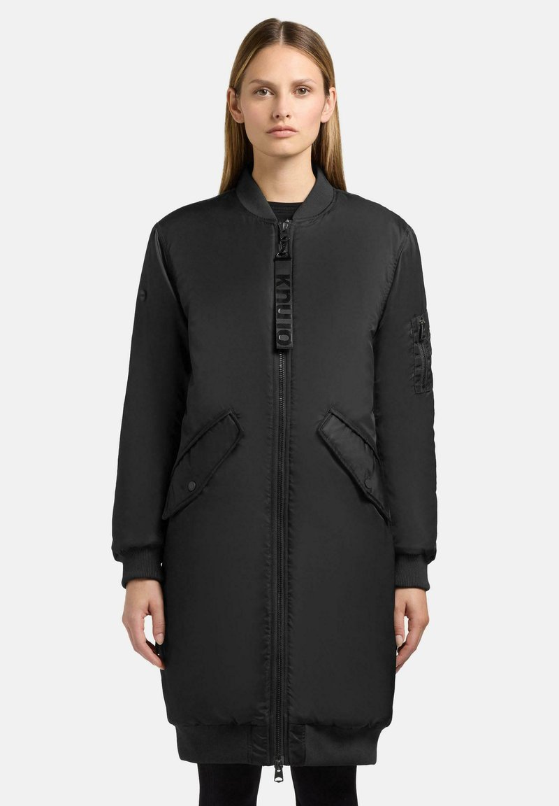 Giacca nera lunga trapuntata con zip frontale, polsini a costine e due tasche frontali con zip laterale. Tessuto liscio e leggero.