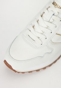 Sneaker bianca con tomaia in pelle testurizzata, design con lacci e suola in gomma. Presenta dettagli azzurri lungo le cuciture.