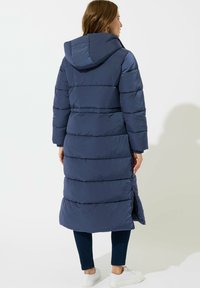 Abrigo de plumas azul marino, largo y con capucha, con un diseño de acolchado horizontal, que cuenta con una cremallera de longitud completa y bolsillos laterales con cremallera.